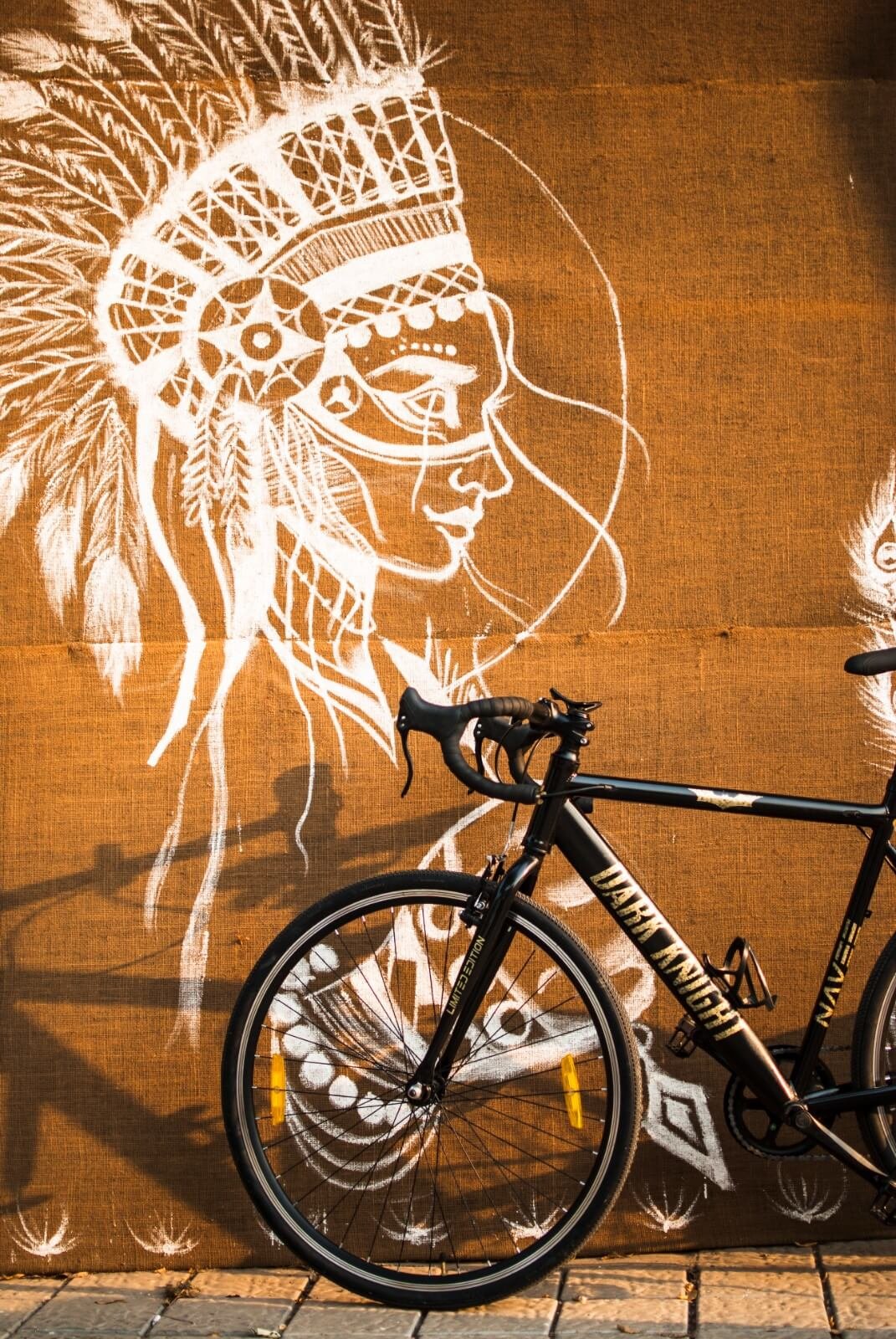 NAVEE MR24 Dark Knight limited edition road bike leaning against a hand-painted mural wall